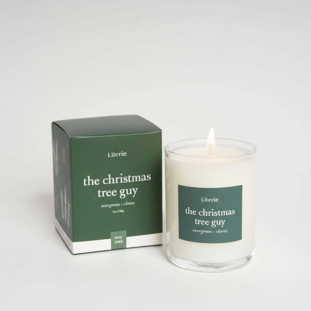 Lit candle and packaging of 'the christmas tree guy' by Literie on a white background